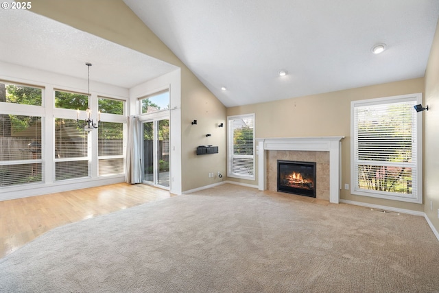 unfurnished living room with carpet flooring, baseboards, vaulted ceiling, a tile fireplace, and recessed lighting