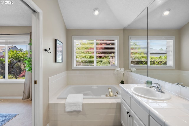bathroom featuring a textured ceiling, a garden tub, healthy amount of natural light, vanity, and recessed lighting