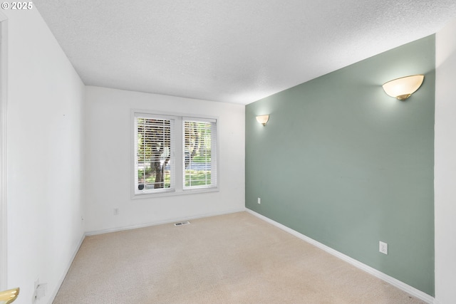 carpeted empty room featuring a textured ceiling and baseboards