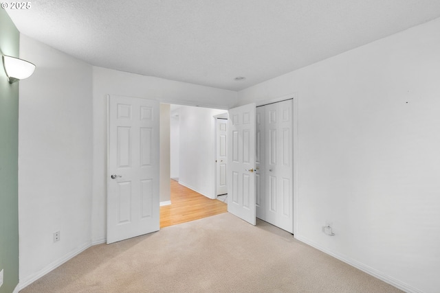 unfurnished bedroom with light carpet, baseboards, and a closet