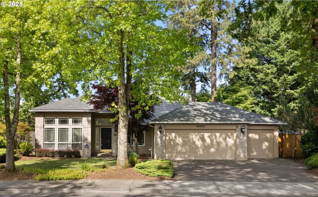 view of front of home featuring a garage, driveway, brick siding, and fence