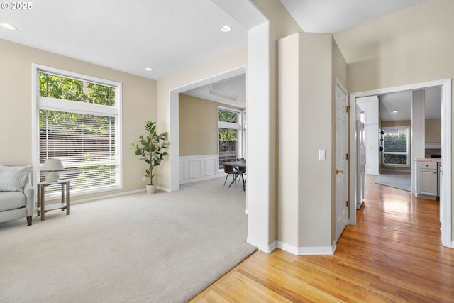sitting room with healthy amount of natural light, recessed lighting, light wood-style flooring, a decorative wall, and wainscoting