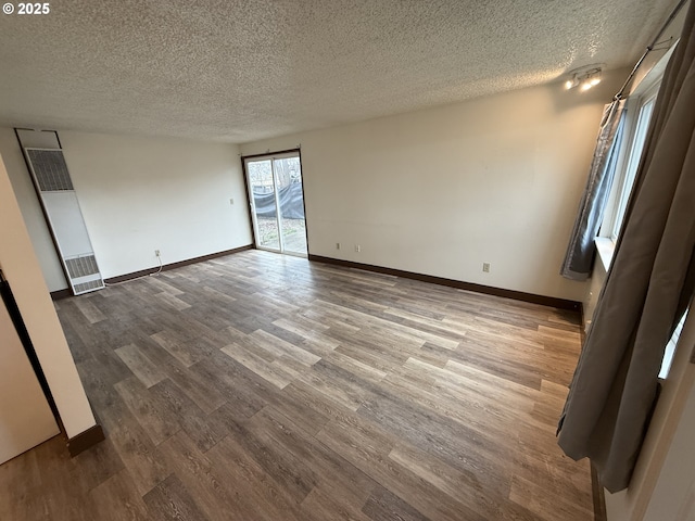 empty room with wood-type flooring and a textured ceiling