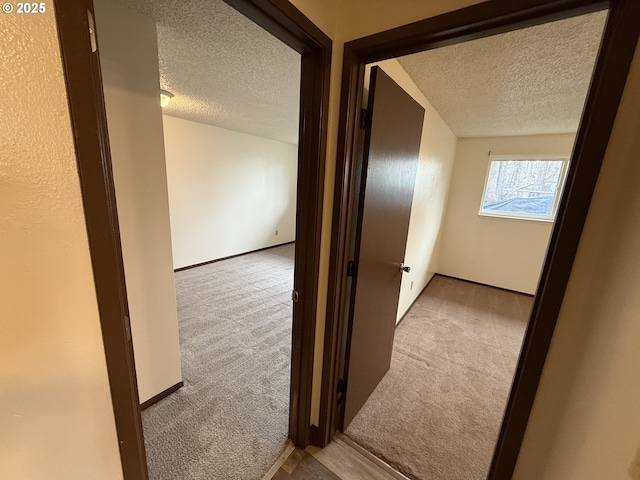 hallway featuring light carpet and a textured ceiling