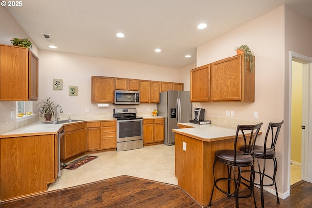 5761 Mt Vernon Rd, Springfield, OR 97478 - kitchen with appliances with stainless steel finishes, a sink, a peninsula, light countertops, and a breakfast bar
