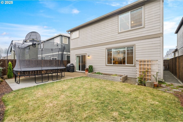 back of property with a patio area, a trampoline, and a lawn