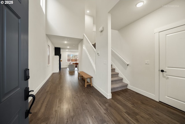 foyer entrance with dark wood-type flooring and a towering ceiling