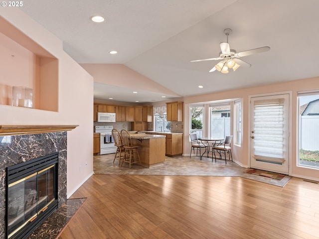 living room with visible vents, vaulted ceiling, a premium fireplace, recessed lighting, and light wood-style flooring