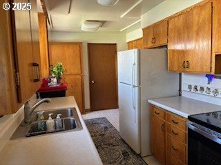 14031 SE Rhone St, Portland, OR 97236 - kitchen featuring range with electric stovetop, a sink, brown cabinets, light countertops, and freestanding refrigerator