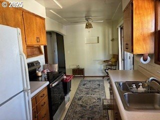 14031 SE Rhone St, Portland, OR 97236 - kitchen with range with electric stovetop, freestanding refrigerator, a sink, brown cabinetry, and a ceiling fan