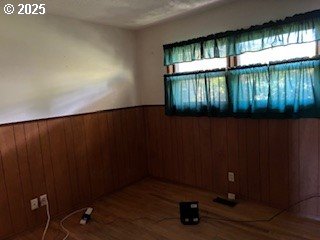 14031 SE Rhone St, Portland, OR 97236 - spare room with healthy amount of natural light, wainscoting, wooden walls, and wood finished floors