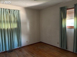 14031 SE Rhone St, Portland, OR 97236 - empty room with wood finished floors and a textured ceiling