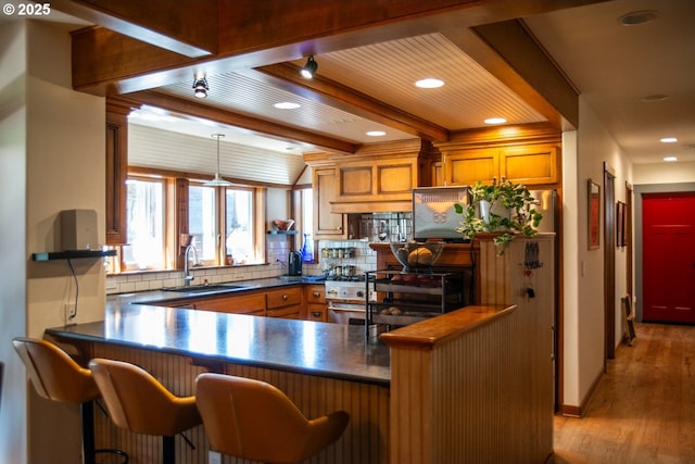 62725 Eagle Rd, Bend, OR 97701 - kitchen featuring backsplash, dark countertops, light wood-type flooring, a sink, and beamed ceiling