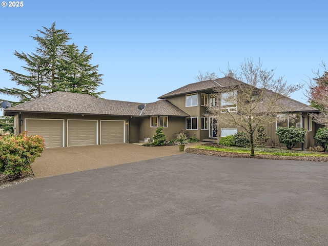 view of front of home featuring an attached garage, driveway, and roof with shingles