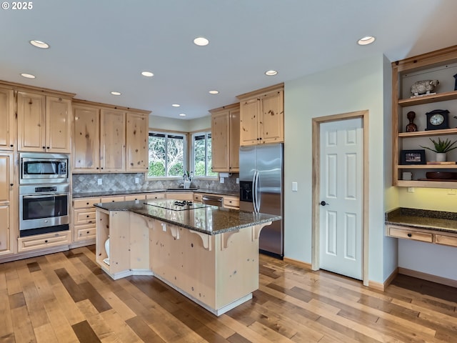 kitchen featuring a center island, a breakfast bar, open shelves, stainless steel appliances, and dark stone countertops