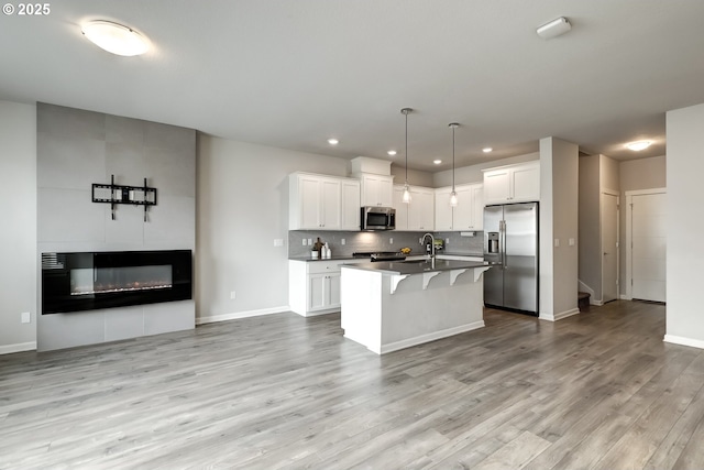 kitchen featuring stainless steel appliances, decorative backsplash, light wood-style floors, a kitchen bar, and open floor plan