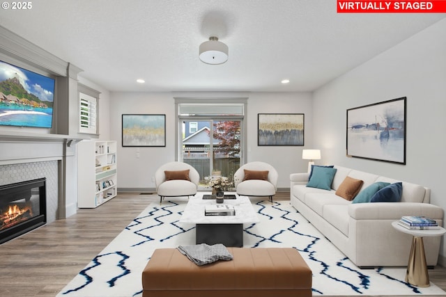 14716 Blue Blossom Way, Oregon City, OR 97045 - living area with light wood-style floors, a glass covered fireplace, healthy amount of natural light, recessed lighting, and a textured ceiling
