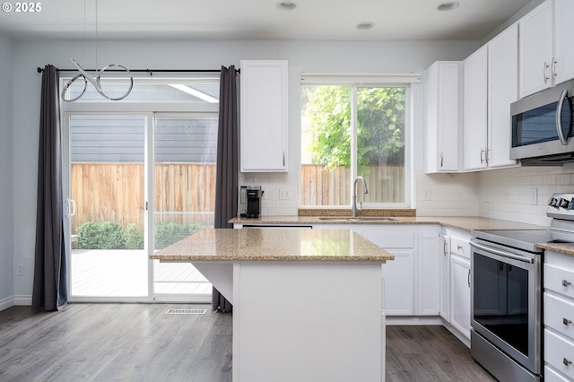 18576 SW Tara Meadows Ct, Beaverton, OR 97078 - kitchen featuring appliances with stainless steel finishes, decorative backsplash, a kitchen island, white cabinets, and recessed lighting