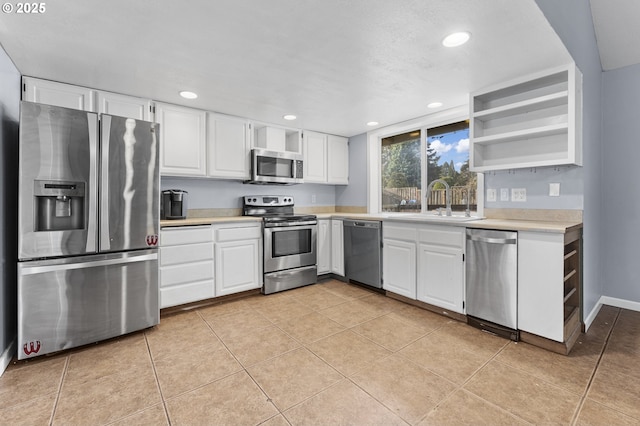 kitchen with sink, white cabinetry, stainless steel appliances, and light tile patterned floors