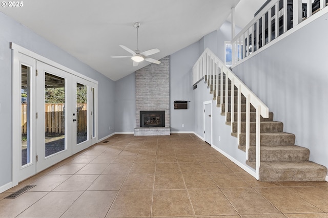 unfurnished living room featuring french doors, a brick fireplace, ceiling fan, light tile patterned floors, and high vaulted ceiling