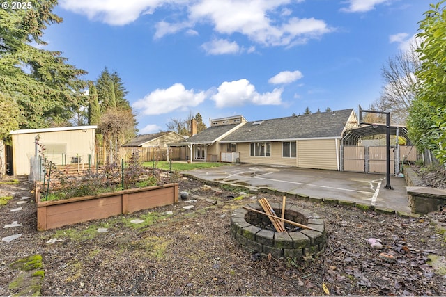 rear view of house featuring a patio, a carport, and an outdoor fire pit