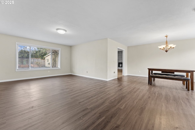 unfurnished living room featuring dark hardwood / wood-style flooring and a chandelier