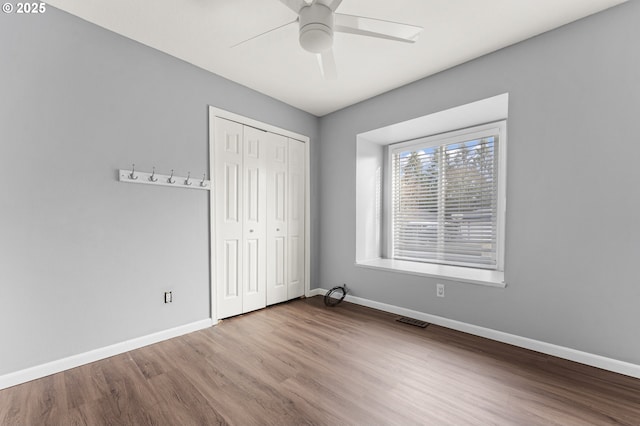 unfurnished bedroom with ceiling fan, light wood-type flooring, and a closet