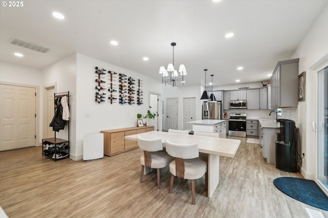 dining room featuring light wood finished floors, baseboards, visible vents, a notable chandelier, and recessed lighting