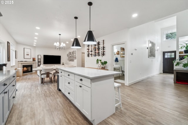 kitchen featuring decorative light fixtures, light countertops, open floor plan, white cabinetry, and a kitchen island