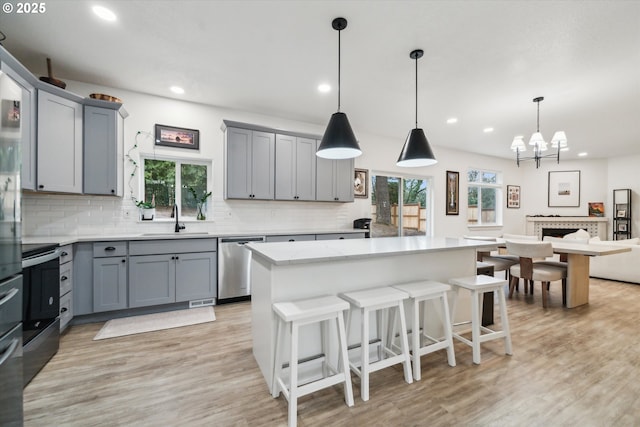 kitchen featuring appliances with stainless steel finishes, a center island, decorative light fixtures, and a sink