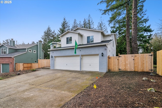 view of front of property featuring brick siding, a gate, fence, a garage, and driveway