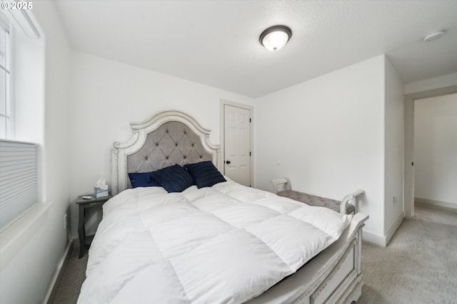 bedroom with light colored carpet and baseboards