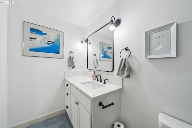 bathroom with toilet, vanity, and baseboards