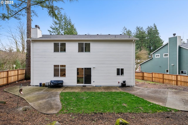 rear view of property with a patio, a chimney, and a fenced backyard