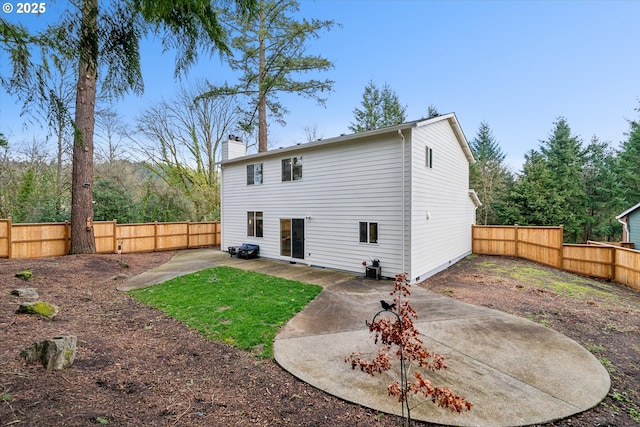 rear view of property featuring a patio, a chimney, and a fenced backyard