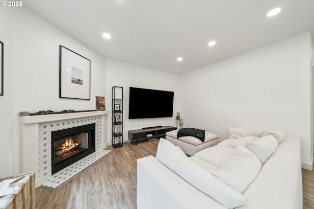 living area with a tiled fireplace, baseboards, wood finished floors, and recessed lighting