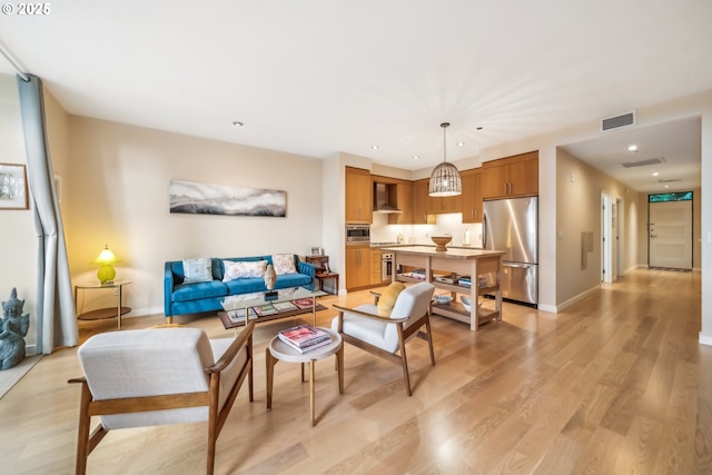 living room with light wood finished floors, visible vents, recessed lighting, and baseboards