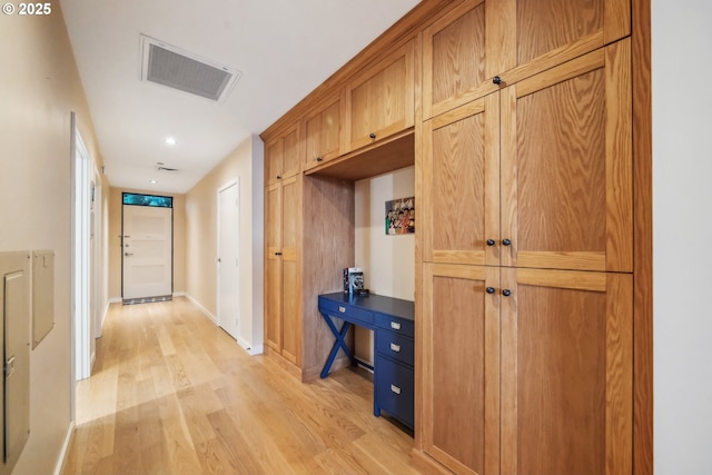 hall featuring visible vents, light wood-type flooring, and baseboards