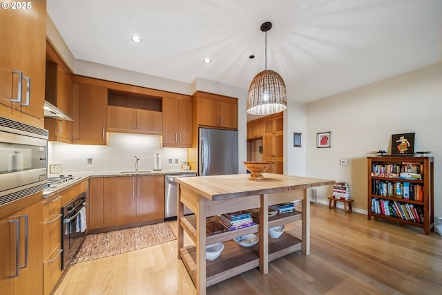 kitchen featuring a sink, light wood-style flooring, appliances with stainless steel finishes, and open shelves