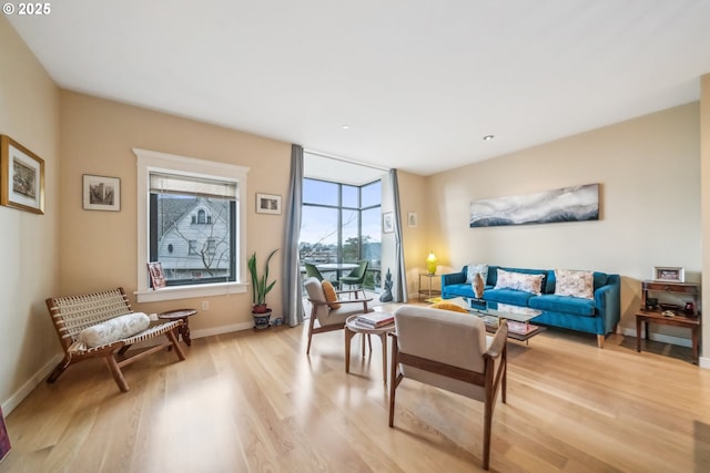 living area with expansive windows, baseboards, and light wood finished floors