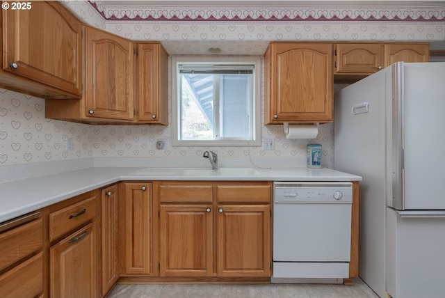 kitchen featuring a sink, white appliances, light countertops, and wallpapered walls