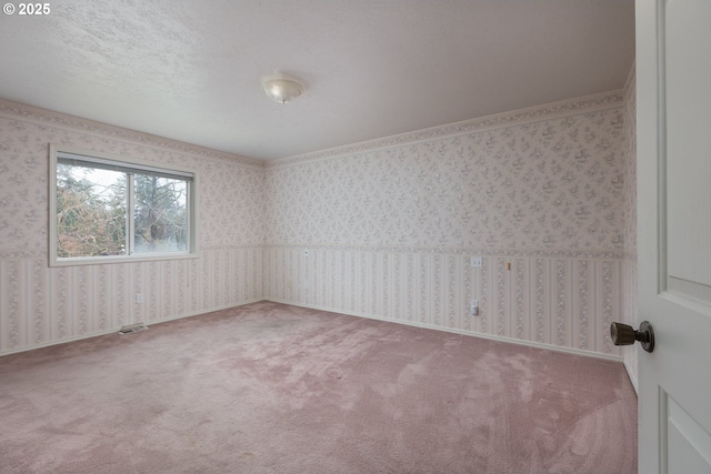 unfurnished room with a textured ceiling, carpet, baseboards, and wallpapered walls