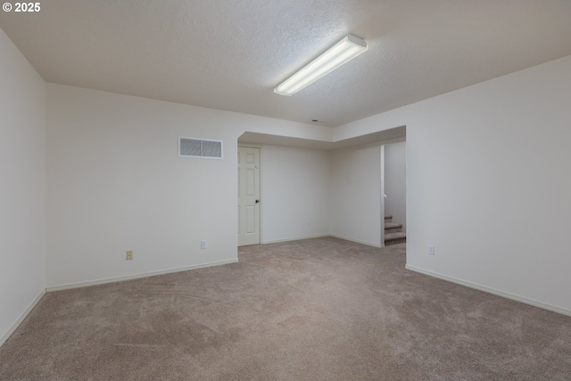 spare room featuring a textured ceiling, carpet flooring, visible vents, baseboards, and stairs