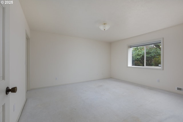 carpeted spare room with visible vents and baseboards