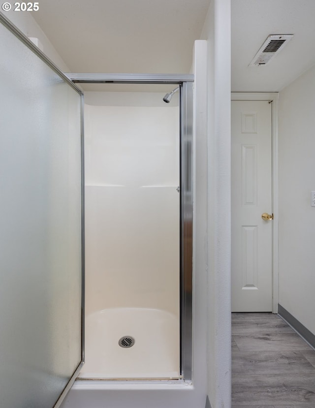 full bath featuring visible vents, a shower stall, and wood finished floors