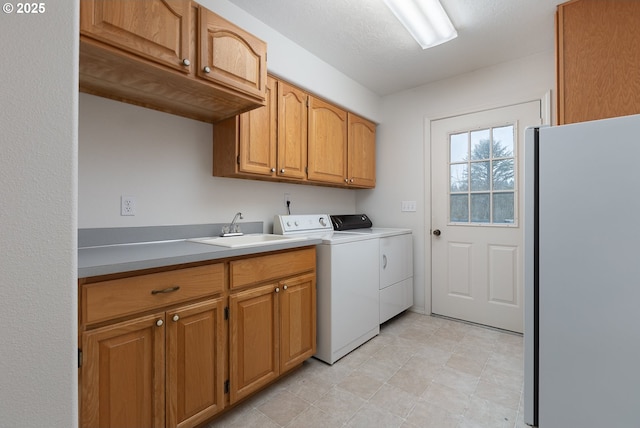 laundry area featuring washing machine and dryer, cabinet space, and a sink