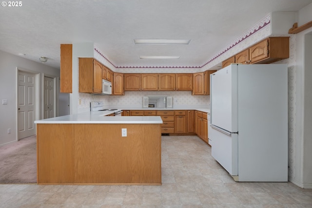 kitchen featuring white appliances, tasteful backsplash, brown cabinets, a peninsula, and light countertops