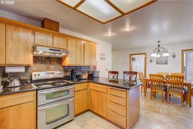 kitchen featuring tasteful backsplash, kitchen peninsula, a notable chandelier, and range with two ovens