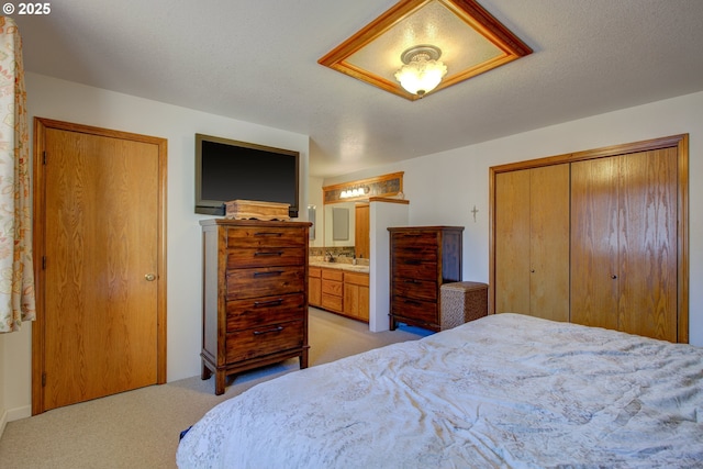 carpeted bedroom featuring a textured ceiling, ensuite bathroom, and a closet