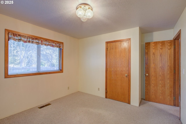 unfurnished bedroom featuring light carpet and a textured ceiling